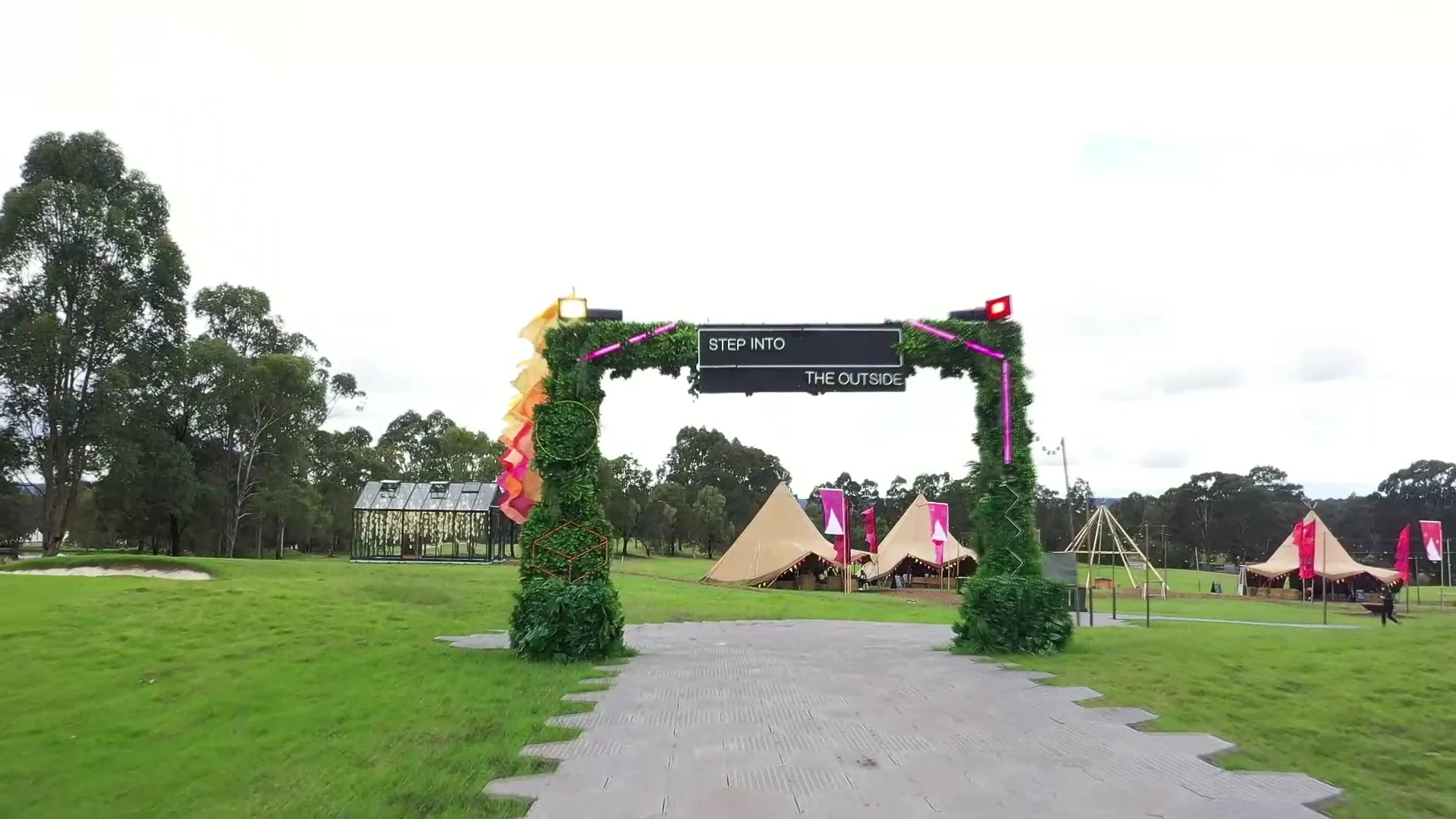 The Step Into The Outside entrance arch at PwC Australia's signature experience, with the tipi village on the green behind it