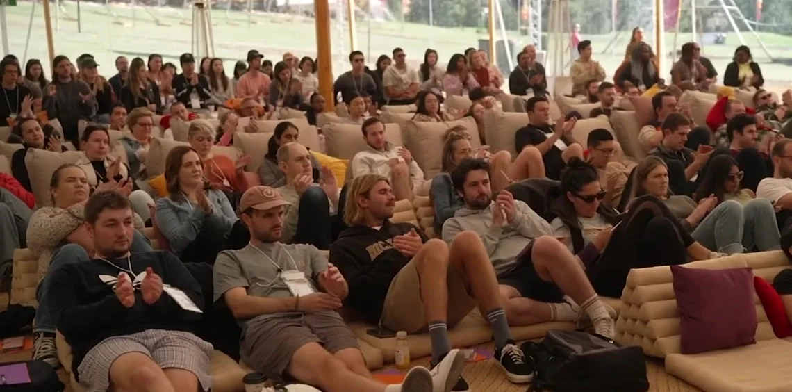 A packed marquee at The Outside, participants seated on cushions and beanbags watching a session