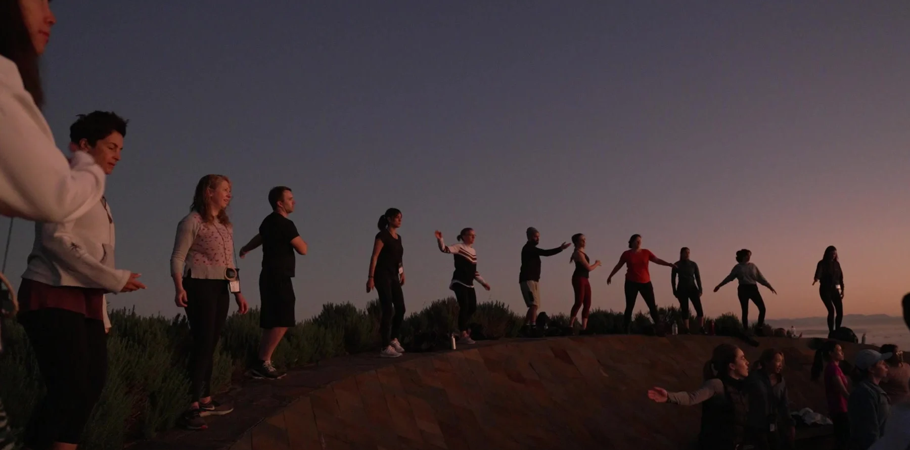 Participants on the ridge at sunrise at The Outside, silhouetted against the valley