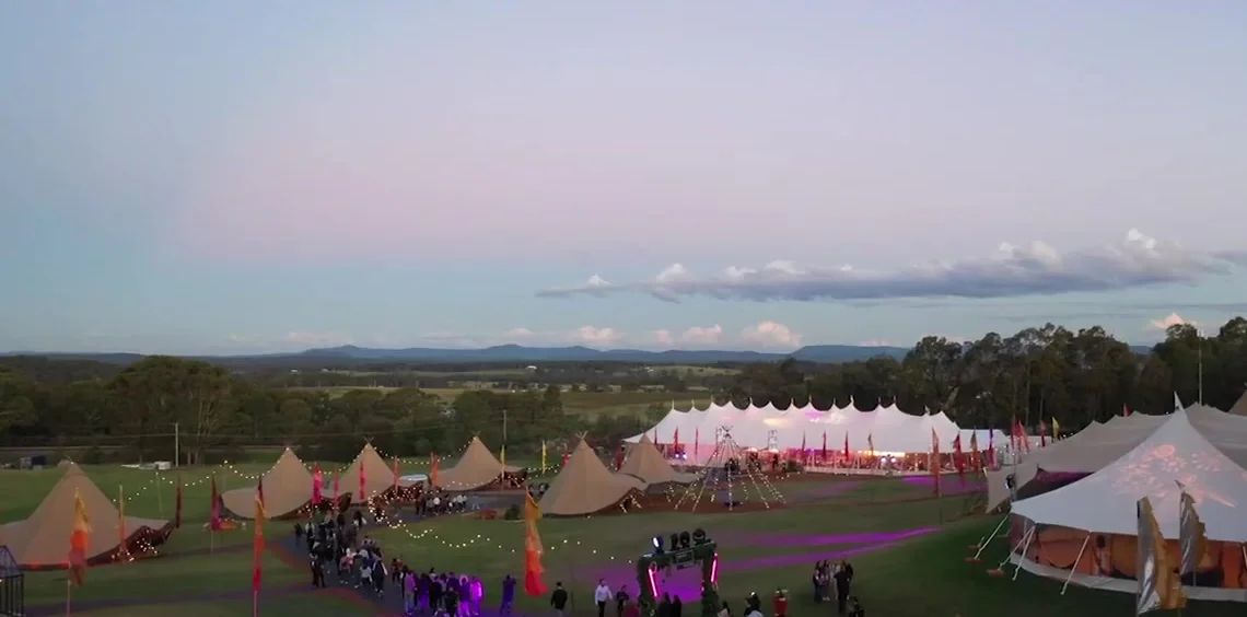 The Outside site at dusk, marquees and tipis lit across the green on Wonnarua Country in the Hunter Valley