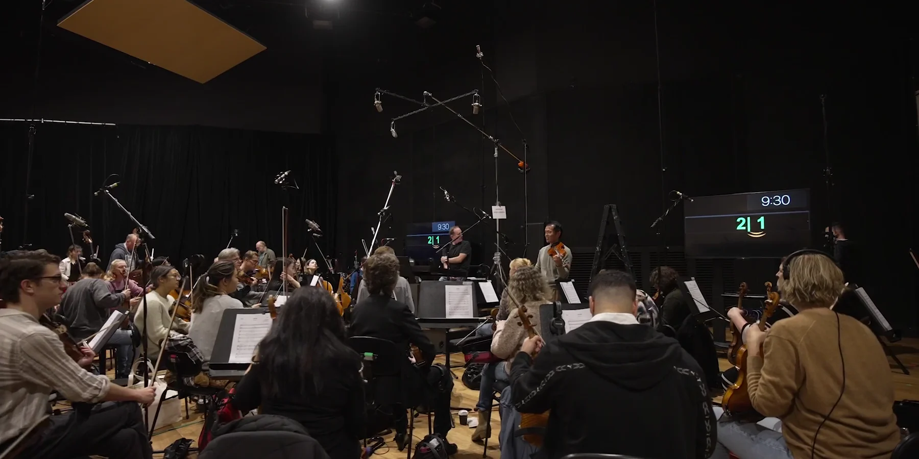 A full orchestra recording a live scoring session at Trackdown Studios, microphones rigged over the players